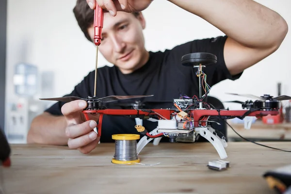 Imagem do homem com chave de fenda fixando helicóptero quadrado na mesa — Fotografia de Stock