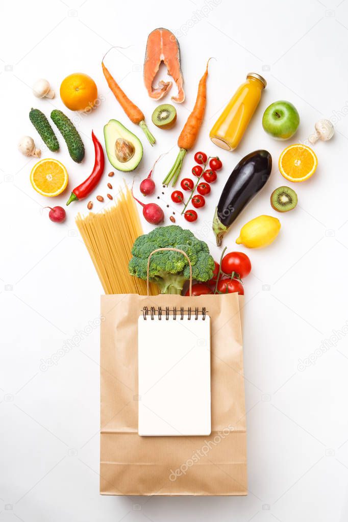 Picture of paper bag with vegetables, fruits and spaghetti isolated on empty white background.