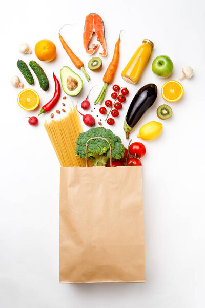Photo of paper bag with vegetables, fruits, fish and spaghetti