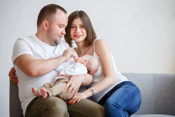 Zdjęcie z szczęśliwych rodziców z nowo narodzonego dziecka w ramionach, siedząc na kanapie — Zdjęcie stockowe