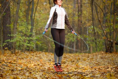 Spor kız sonbahar ormandaki iple atlama yan görünüm