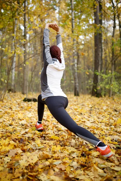 Herbstfoto aus dem Rücken einer sportlichen Frau, die sich im Wald dehnt — Stockfoto