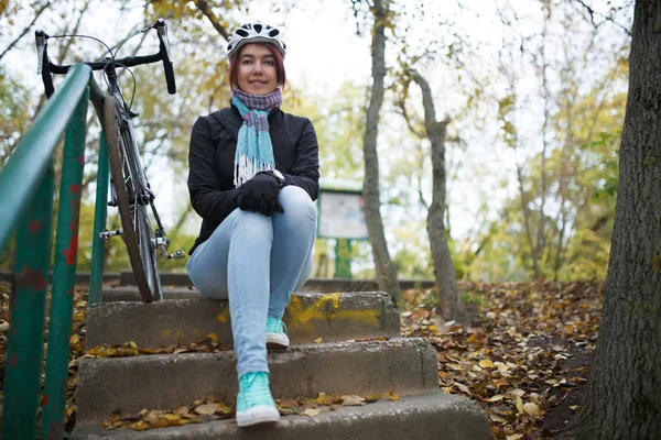 Фото девушки, сидящей на лестнице рядом с велосипедом — стоковое фото
