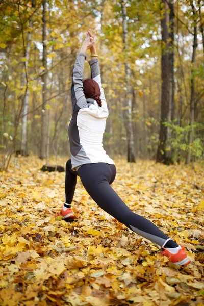 Imagen de otoño de la espalda de la mujer deportiva que se extiende en el bosque — Foto de Stock