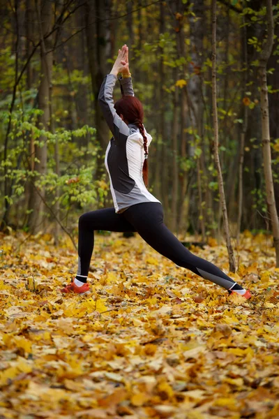 Foto de outono de menina desportiva que se estende na floresta de manhã contra o fundo das árvores — Fotografia de Stock