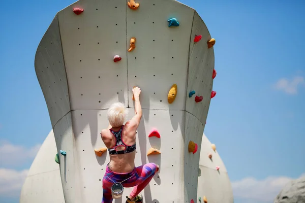 Photo from back of athlete with short haircut on wall for rock climbing against blue sky — Stock Photo, Image