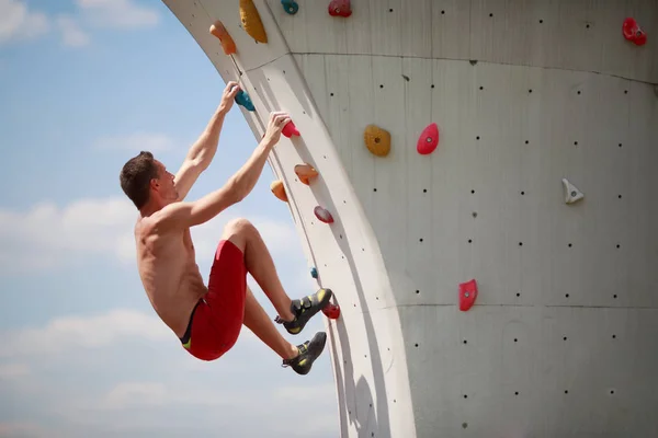 Фото спортивного чоловіка, який займається спортом на стіні для сходження на хмарне небо — стокове фото