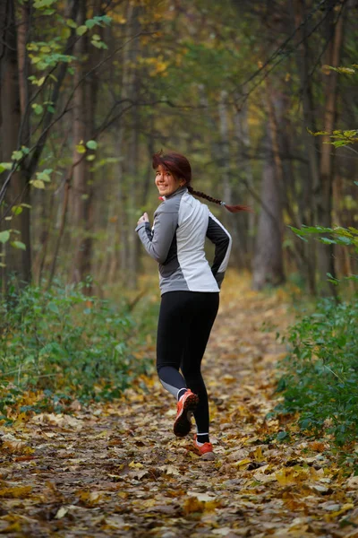 Photo of brunette in sportswear on run in autumn afternoon — Stock Photo, Image