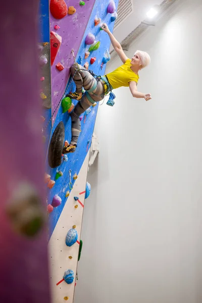 Foto eines lächelnden Mädchens mit Tasche zum Klettern an der Wand in der Turnhalle — Stockfoto