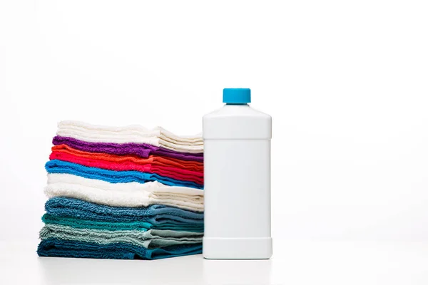 Foto av en flaska rengöringsmedel och flerfärgade handdukar på ren, vit bakgrund — Stockfoto