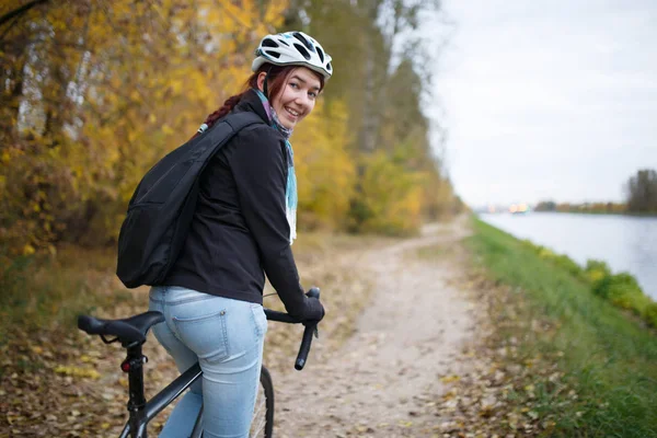 Foto einer lächelnden Frau mit Helm und Rucksack auf dem Fahrrad — Stockfoto