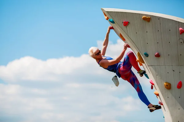 Foto einer jungen sportlichen Frau, die an einem felsigen Sommertag klettert — Stockfoto