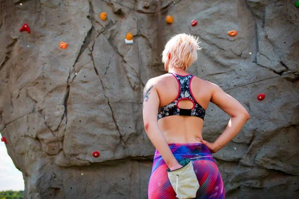 Фото со спины спортивной девушки с сумкой против камня — стоковое фото