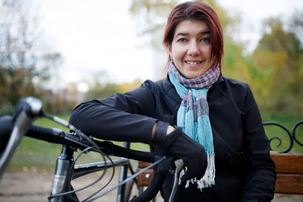 Image of smiling woman sitting on bench next to bicycle — Stock Photo, Image