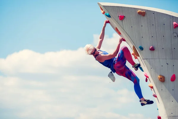 Bild einer jungen sportlichen Frau, die an einem felsigen Sommertag klettert — Stockfoto