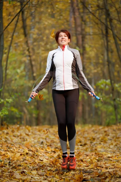 Celovečerní podoba mladá dívka, která skočila s lanem na podzimní les — Stock fotografie