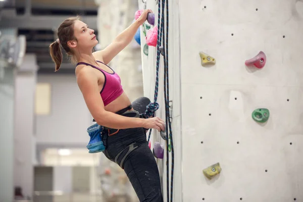 Foto einer jungen sportlichen Frau, die an einer Wand für das Klettern übt — Stockfoto