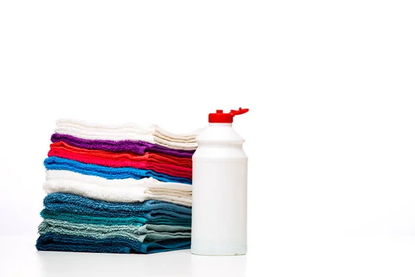 Foto de uma garrafa de detergente líquido e toalhas multicoloridas em fundo branco limpo — Fotografia de Stock