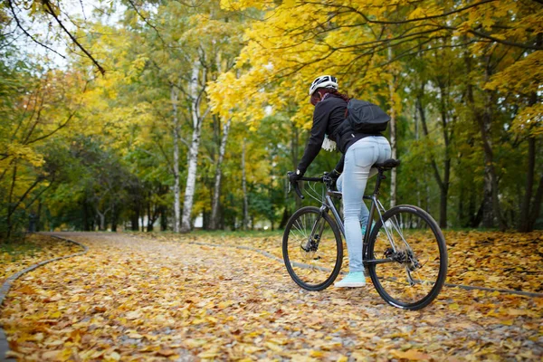 Photo of woman in helmet riding bicycle in autumn — Stock Photo, Image