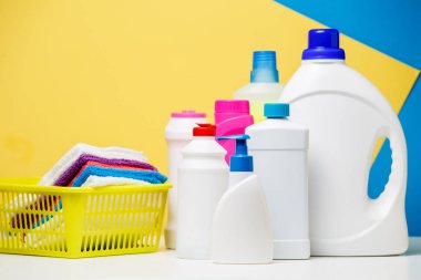 Temizlik ürünleri ve çok renkli havlu izole mavi, sarı zemin üzerine sepet içinde birkaç şişe fotoğrafı