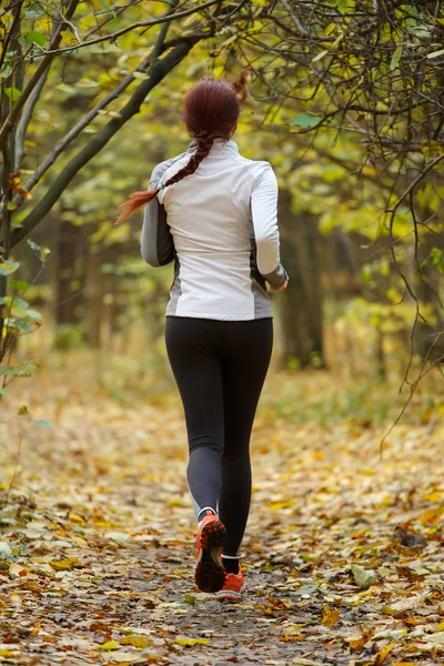 Foto ze zadní strany mladá dívka běží přes podzimní park — Stock fotografie