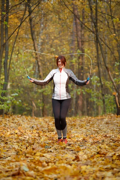 Image of sporty brunette jumping rope at autumn forest — Stock Photo, Image