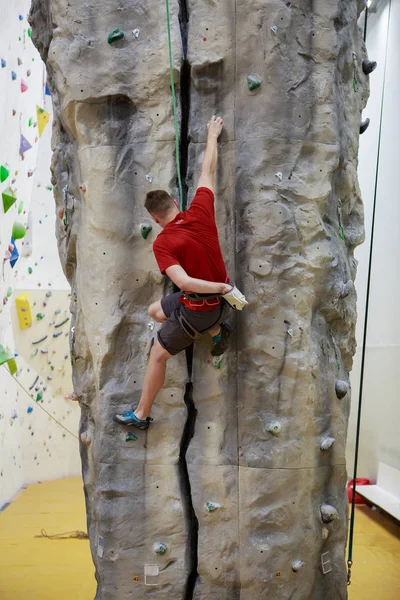 Foto von hinten: Mann klettert in Turnhalle auf Felsbrocken — Stockfoto