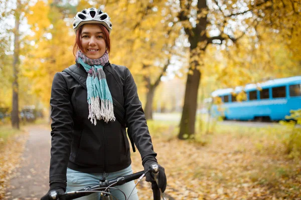 Donna sorridente in casco in bicicletta sullo sfondo del tram blu — Foto Stock