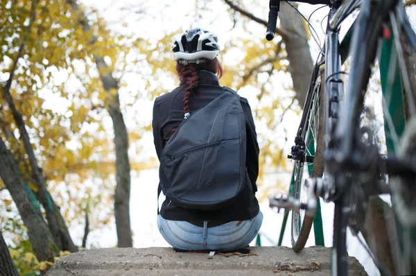 Bild vom Rücken des Mädchens, das am Ufer des Teiches neben dem Fahrrad sitzt — Stockfoto