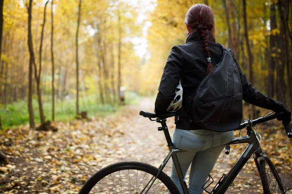 Photo from back of brunette in jeans next to bicycle — Stock Photo, Image