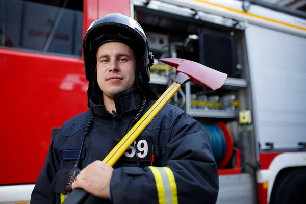 Foto de bombero con martillo contra máquina de fuego —  Fotos de Stock