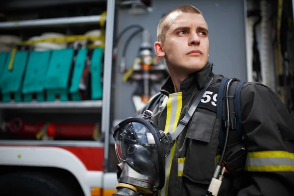 Φωτογραφία: πυροσβέστης στέκεται κοντά σε πυροσβεστικό όχημα με ΠΥΡΟΣΒΕΣΤΙΚΗΣ — Φωτογραφία Αρχείου