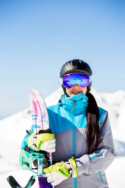 Napszemüveg napszemüveget visel, a snowboard, a háttérben a havas hegyek, mosolygós nő portréja — Stock Fotó