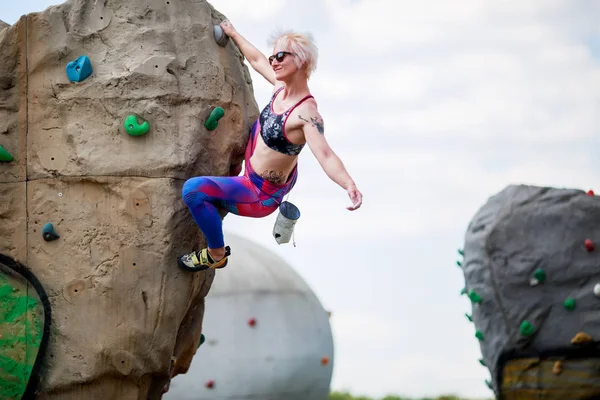 Foto von Sport-Blondine auf Kletterfelsen gegen Himmel mit Wolken engagiert — Stockfoto