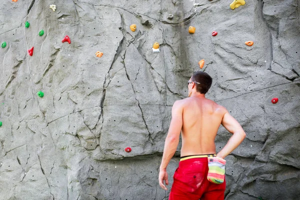 Zdjęcie z tyłu mężczyzna wspinacz w czerwonych spodenkach na tle boulder do wspinaczki — Zdjęcie stockowe