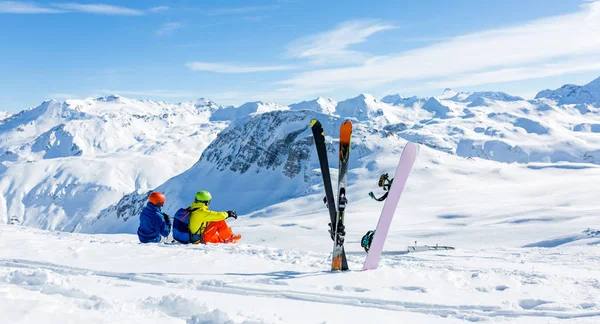 Snowboardåkare och skidåkare sittande på snö och se på berg — Stockfoto