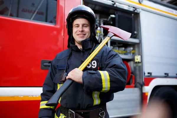 Photo of happy fireman with hammer against fire machine