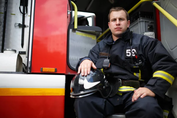 Foto eines jungen Feuerwehrmannes, der in Feuerwehrauto in die Kamera blickt — Stockfoto