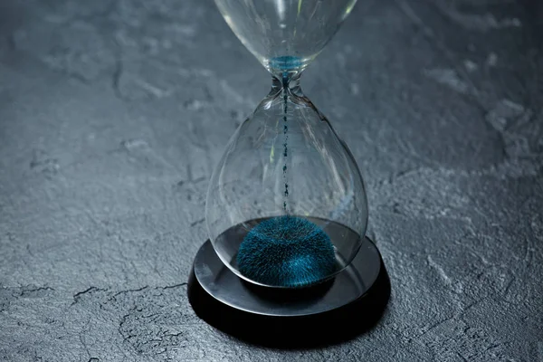 Foto de ampulheta de vidro com areia azul sobre fundo de pedra preta — Fotografia de Stock