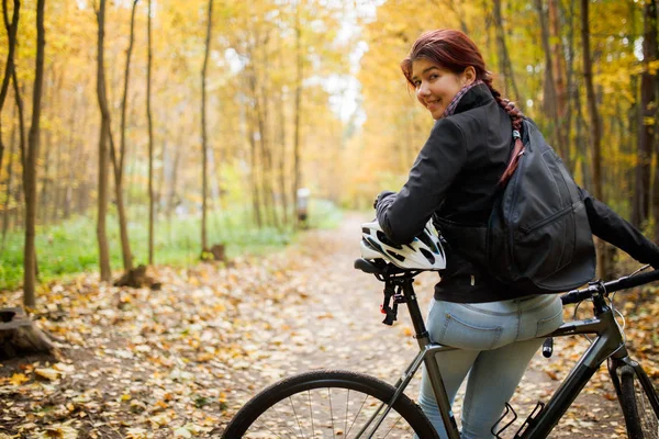 Photo of smiling brunette in jeans next to bicycle — Stock Photo, Image