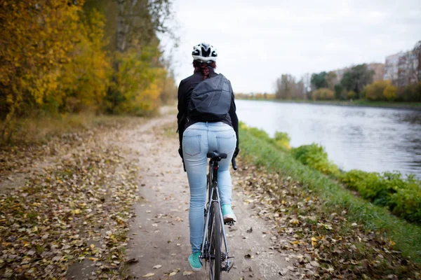 Foto vom Rücken eines Mädchens mit Helm beim Fahrradfahren am Flussufer — Stockfoto
