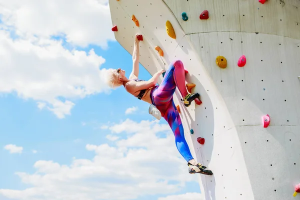 Foto de jovem loira no treino na parede de escalada — Fotografia de Stock