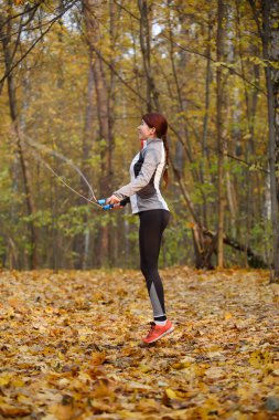 Genç kadın ile sonbahar orman ip atlama tam boy görüntü
