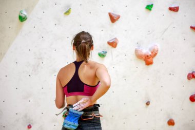 Photo from back of girl athlete with bag of talc against background of wall for rock climbing clipart