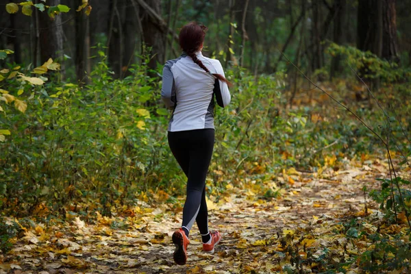 Photo from back of woman in sports clothes on run in autumn — Stock Photo, Image