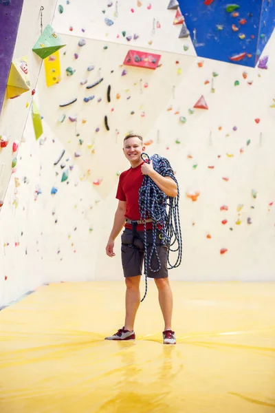 Foto des jungen Mannes in Sportkleidung und mit Schutzseil in der Nähe der Kletterwand — Stockfoto