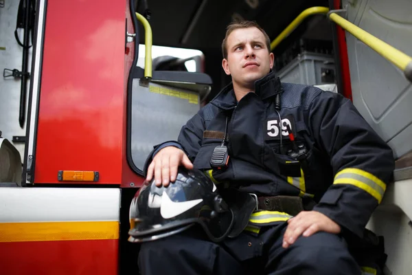 Foto di pompiere guardando l'uomo che guarda lontano seduto nel motore del fuoco — Foto Stock