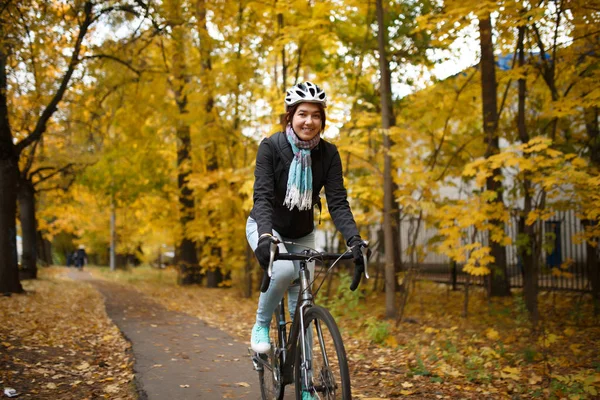 Foto de mulher no capacete andando de bicicleta ao longo do caminho — Fotografia de Stock