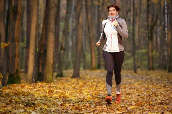 Foto von sportlichen Brünette läuft durch Herbst Park — Stockfoto