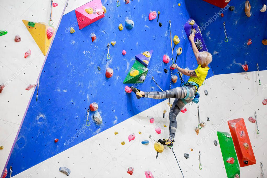 Photo from below of young girl exercising on climbing wall